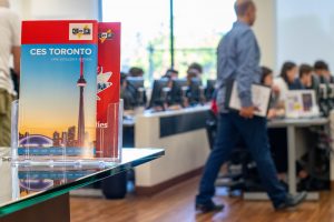 Locandina informativa della scuola CES di Toronto. Sullo sfondo si vede un'aula computer