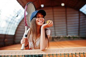 Ragazza ascolta indicazioni dall'istruttore di tennis a Monte Baldo durante il programma Tennis e Sport